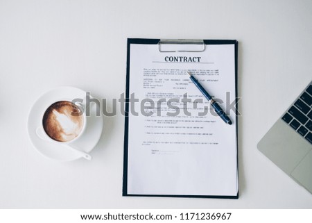 Pen on contract sheet and business document ,near coffee cup and laptop computer in home office, Business and Office concept.
