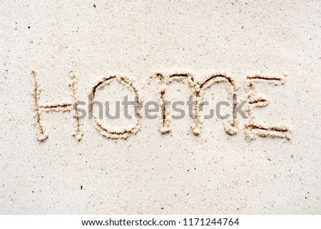 Handwriting words "Home" on sand of beach