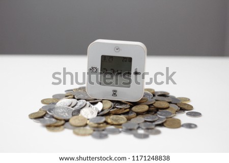 digital clock the latest technology with coins. time is money concept.