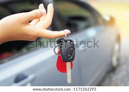 The car owner holds the car keys. The car is parked behind. Buy & Sell Car      