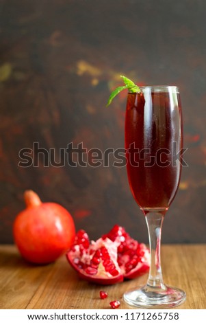 Glass of pomegranate juice with Broken and whole pomegranates on rustic wooden board