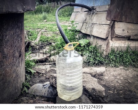 Water supply shortage and climate change threats: collecting drinking water with 5 liter plastic water bottle from a well in a rural area in Central Asia Royalty-Free Stock Photo #1171274359
