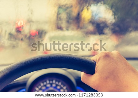 vintage tone image of people driving car on evening time with raindrop on glass  for background usage.(take photo from inside)