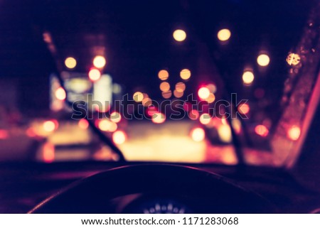vintage tone blur image of people driving car on night time for background usage.(take photo from inside)
