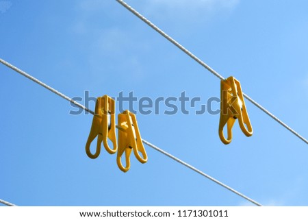 Yellow clothespins hang on a rope against a blue sky.