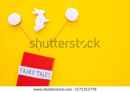 Fairy tales book near candies on yellow background top view space for text