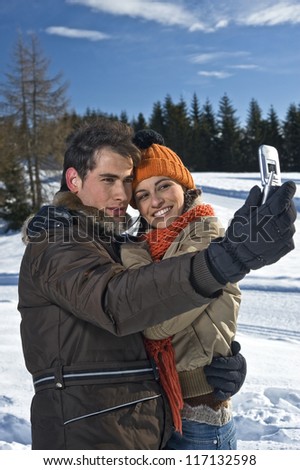 Young couple taking photos on the snow
