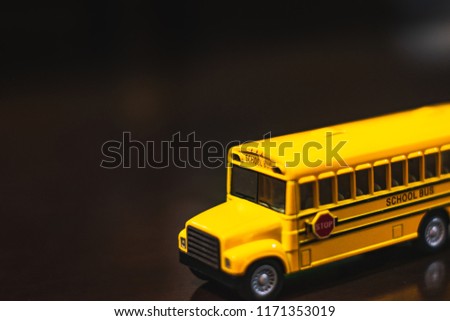 Toy school bus on a dark brown isolated background. Back to school concept.