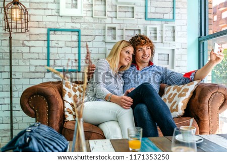 Young couple taking selfie on a sofa in a coffee shop