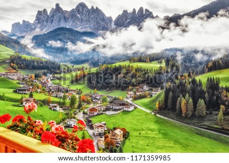 Italy, Dolomite mountains. Fascinating Alpine Village - Santa Maddalena, amazing view from balcony of hotel on flowers, green valley, Alps Odle in distance. Landscape photography, travel background.