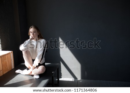 Girl is sitting on a table on a black background.