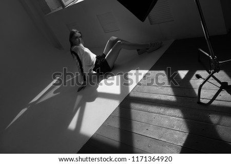 Model sits on the floor in a professional photo studio.