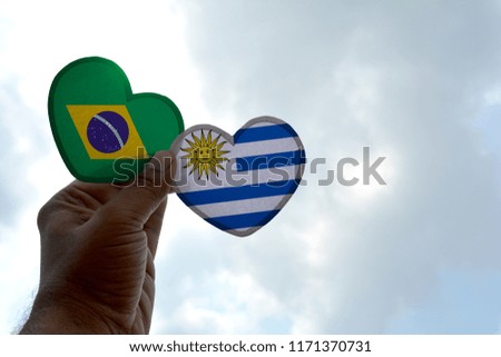 Hand holds a heart Shape Brazil and Uruguay flag, love between two countries