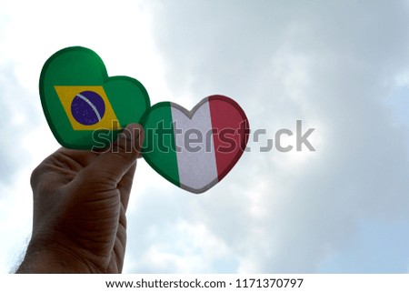 Hand holds a heart Shape Brazil and Italy flag, love between two countries