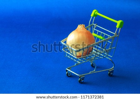 on a blue fabric background there is a basket from a supermarket in which they laid an unpurified bulb, yellow on blue