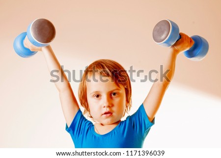 Strong child with dumbbells. Photo of sporty girl in sportswear. Sport lifestyle, health, power, success concept.