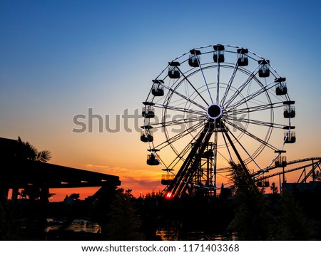 Ferris wheel in sunset.  Big wheel with cabins. Circle construction to beautiful panoramatic view. Summer  amusement ride for enjoy holidays. 