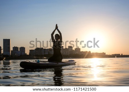 silhouette of a slender girl engaged in yoga on a city background