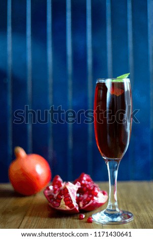 Glass of pomegranate juice with pomegranates on rustic blue background