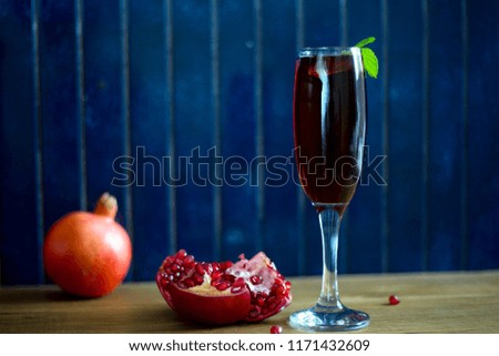 Glass of pomegranate juice with pomegranates on a rustic deep blue background