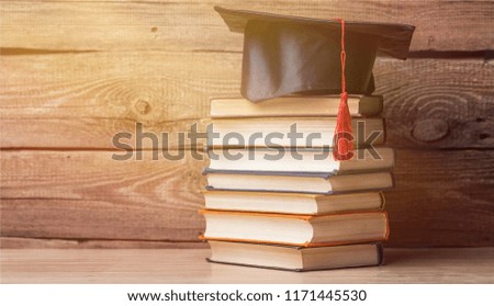 Graduation hat and stacks of books, close-up view