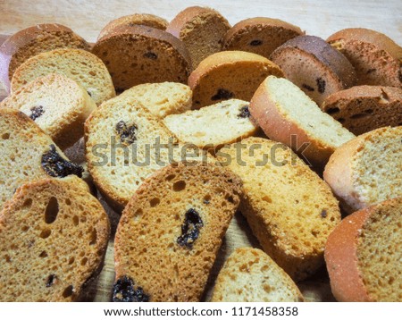 Freshly baked vanilla tasty crackers with raisins lie on a wooden table top and a dark background.