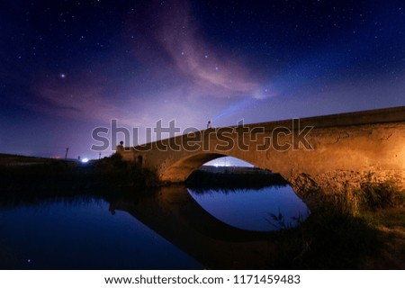 Man crossing bridge in the countryside at night