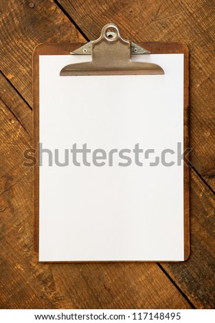An vintage clipboard on a old wooden desk, with regular white blank paper. Royalty-Free Stock Photo #117148495