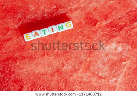 The inscription of the eating is made of cubes with letters lying on a watermelon