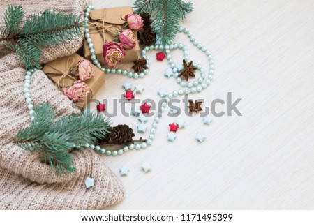 Christmas composition. Gifts, wool blanket, cones, badon, Christmas tree, beads and roses on a light wood background