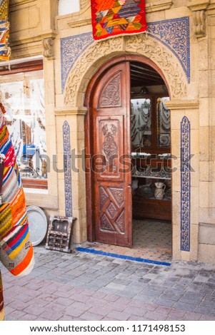The carved door was made by an arch and framed by a blue mosaic. Entrance to the jewelry store. Moroccan style. Africa, Morocco, Essaouira

