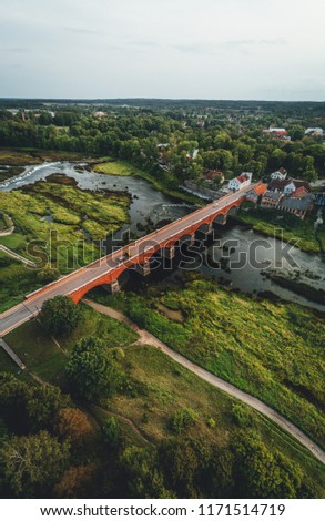 Aerial view on old red brick bridge over river Venta in Kuldiga, latvia, Small european city. Longest waterfall in europe Ventas rumba captured with drone, 