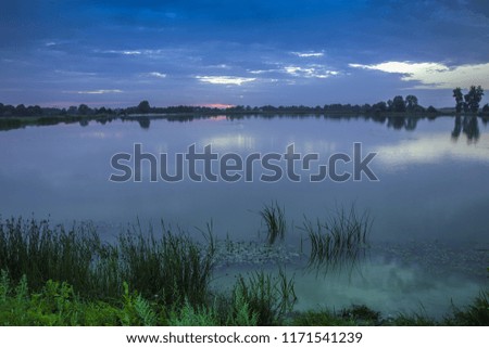 Evening view of a calm lake and sky with clouds after sunset
