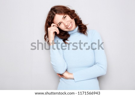 Portrait of an attractive young woman smiling against gray background