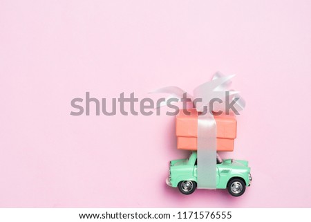 Vintage car carry a  gift box on color background and top wood table for Christmas and The New Year and Valentine's day .Decoration love heart .
