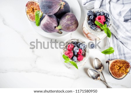 Healthy detox breakfast appetizer - yoghurt smoothie or milkshake with figs, blueberries, raspberries chia seeds, white marble background, copy space