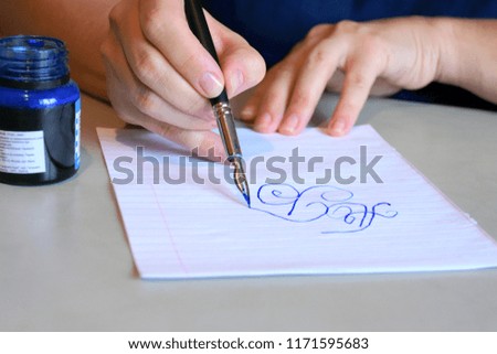 Woman writing blue ink letters by pen with steel nib 