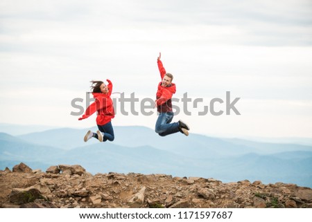 Young happy couple jumping in the background of the mountain.
guy girl jumping happy in the mountains with a breathtaking view. in red clothes. Valentine's Day. stand with your back