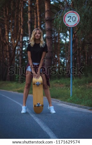 Blonde girl in a black T-shirt and white shorts skates on a skateboard. Street style. Summer