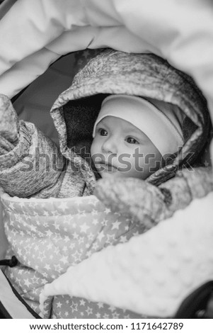 a cute little baby with a trusting gaze dressed in a hat and tempered clothes lying in a bowl and looking at her mom with clear eyes.