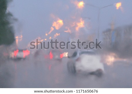 Blurred cars and light bokeh on the road with reflection from wet ground after the rain storm.