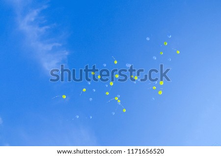Festive multi-colored balloons in the blue sky with 
clouds