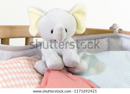 high angle view of teddy elephant, other toys and pillows in baby crib at home