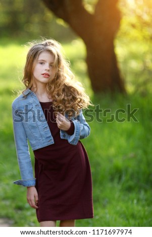 Portrait of a beautiful young little girl on the background of summer park