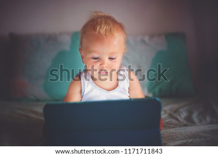 Little baby boy, playing on tablet at home, watching cartoon