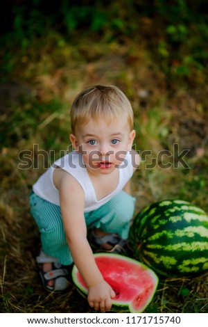 little baby eating watermelon outdoors.Child eating watermelon in summer park.Young blond boy has healthy eating habits.little boy with watermelon, series of happy child pictures eat watermelon .