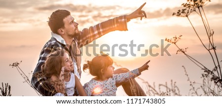 Happy loving family, dad playing with two little cute daughters at sunset sitting on a high beautiful mountain, the concept of family relationships and friendship