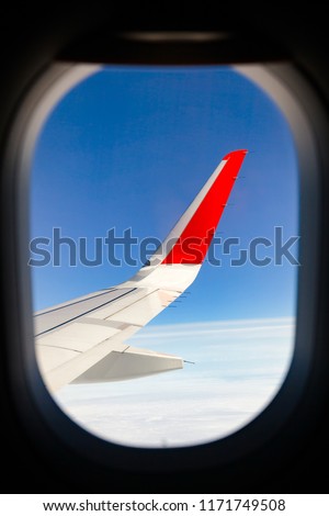 Airliner wing as seen through window of flying airplane