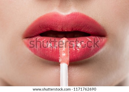 close up of young woman applying lip gloss