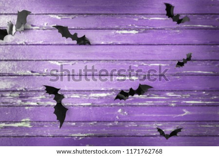 halloween, decoration and scary concept - black bats flying over ultra violet shabby boards background